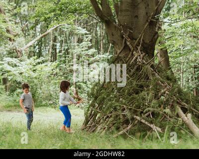 caucasian child in a hut made of branches and leaves Stock Photo