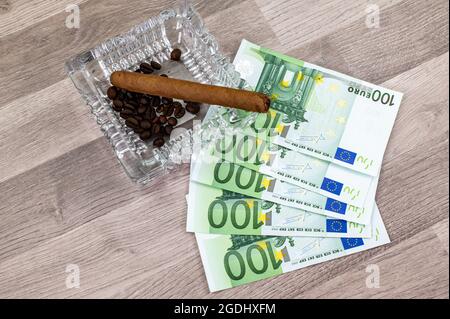 100 euro bills and ashtray with cigar on wooden table Stock Photo