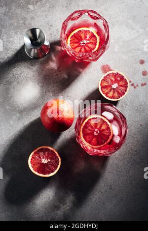 Negroni cocktail with ice cubes and blood orange on a dark background, top view.