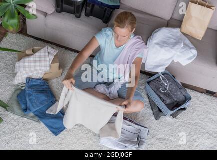 Woman packs in boxes clothes and products for charity and donation. Stock Photo
