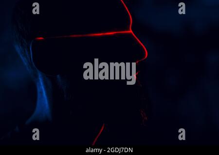 Man in dark with face illuminated by scan red laser on contour. Stock Photo