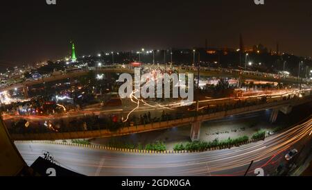 Lahore, Pakistan. 14th Aug, 2021. A stunning view of Punjab assembly, Wapda house, Minar e Pakistan, National College of Arts and other buildings illuminated with the colorful lights as large number of Pakistani people holding national flags as they celebrate midnight 75th Independence Day in Lahore. Preparations across the country are underway to celebrate the 75th Independence Day with traditional zeal and enthusiasm. The country gained its independence from the British rule on August 14, 1947. During the celebration, people parade and dress-up in green and white, which are Pakistan's offici Stock Photo