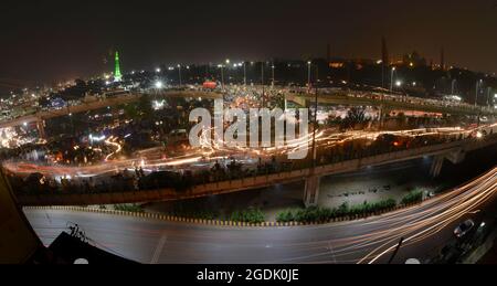 Lahore, Pakistan. 14th Aug, 2021. A stunning view of Punjab assembly, Wapda house, Minar e Pakistan, National College of Arts and other buildings illuminated with the colorful lights as large number of Pakistani people holding national flags as they celebrate midnight 75th Independence Day in Lahore. Preparations across the country are underway to celebrate the 75th Independence Day with traditional zeal and enthusiasm. The country gained its independence from the British rule on August 14, 1947. During the celebration, people parade and dress-up in green and white, which are Pakistan's offici Stock Photo