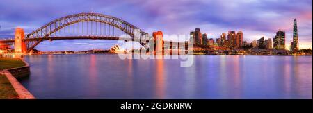 WIde architectural panorama of City of Sydney waterfront on shores of Sydney harbour with major landmarks at sunset. Stock Photo