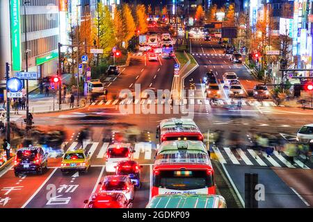 Tokyo, Japan - 2 January 2020: Crowds of unrecognisable blurred people crossing busy city street in Tokyo Shinjuku suburb at night. Stock Photo