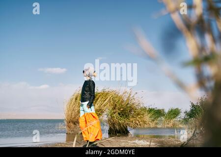 asian woman tourist standing by a lake looking at view under blue sky Stock Photo