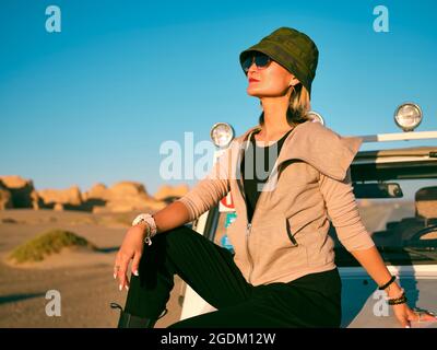 fashionable asian woman sitting on the hood of a car in national geological park Stock Photo
