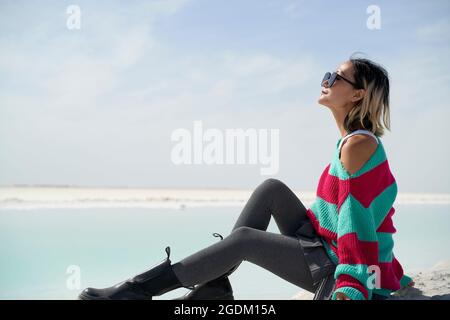 side view of asian woman tourist sitting by a salt lake looking at view Stock Photo