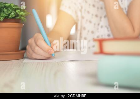 Woman writing on paper, concept of home education, wooden table with notebook Stock Photo
