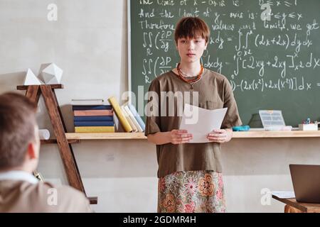 Student presenting her report to other students during lesson in the classroom Stock Photo