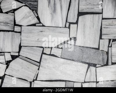 Top view of the old floor, made of various sized pieces of white and gray marble. Abstract black and white monochrome mosaic background. Stock Photo