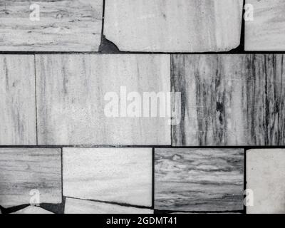 Top view of the old floor, made of various sized pieces of white and gray marble. Abstract black and white monochrome mosaic background. Stock Photo