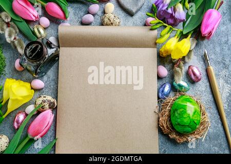 Colorful flowers and painted Easter eggs on grey, stone background. Copy space. Stock Photo