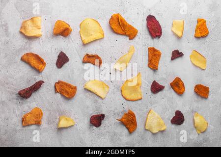 Layered rows of vegetable chips from potatoes, beets and carrots on a concrete background top view Stock Photo
