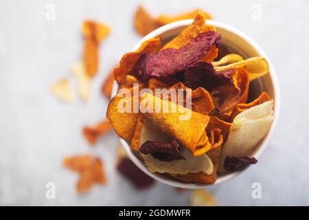 Vegetable organic chips made from potatoes, beets and carrots in a white glass for a snack, top view Stock Photo