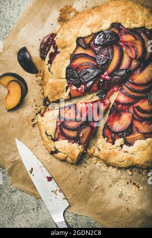 Gluten-free plum galette pie with slice cut on concrete background Stock Photo