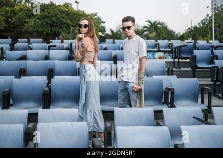 Stylish Couple standing in the stadium. Wearing sunglasses and casual clothes. Looking at camera with copy space. Millennials. High quality photo Stock Photo