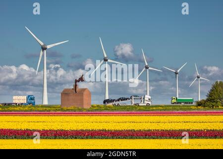 The Netherlands, Nagele, Trucks and cars on highway A6. Artwork. Flowering tulip fields. Spring, wind turbines. Stock Photo