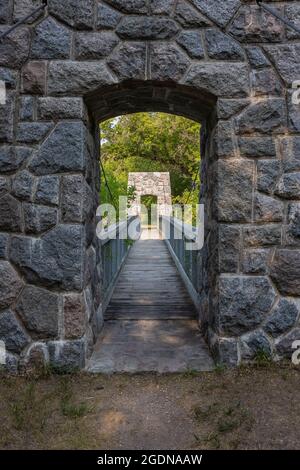 A pedestrian swing bridge on a hiking trail in the woods. Stock Photo