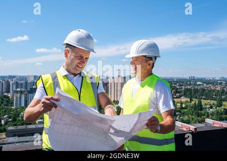 Male engineers reading blueprint together Stock Photo