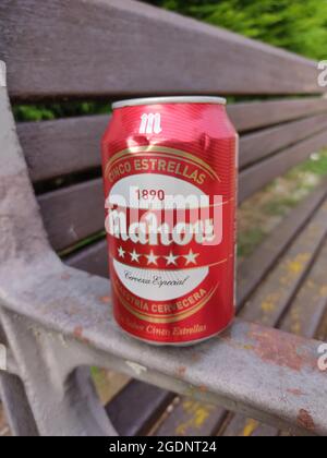 GRADO, SPAIN - Jul 27, 2021: A closeup of a Mahon beer can on a rustic park bench in Grado, Spain Stock Photo