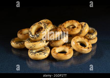 Small bagels with a poppy on the table with a reflection. Food products on a black background Stock Photo