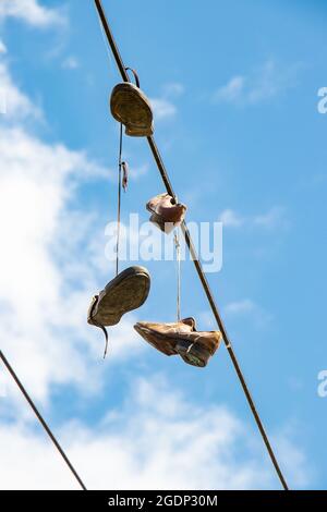 sneakers tied to overhead wires hanging against a blue sky in Seattle, USA Stock Photo