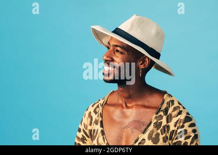 Happy man in white hat standing against blue background looking away Stock Photo