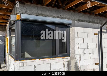 Newly installed corner window with roller shutters in the house under construction. Stock Photo