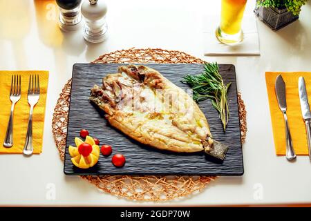 Grilled white fish served on a square stone plate Stock Photo