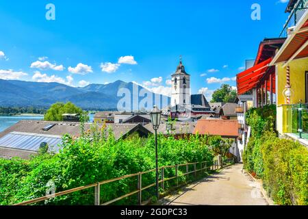 View of St. Wolfgang catholic church in the summer through narrow street in St. Wolfgang im Salzkammergut, Austria. St. Wolfgang is a popular lakeside Stock Photo