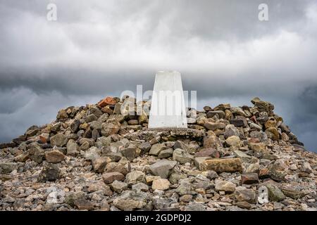 Triangulation pillar (trig point) and cairn at the summit of Windy Gyle on the England Scotland border in the Cheviot hills, Northumberland. Stock Photo