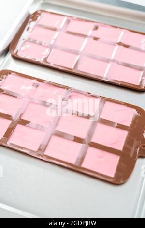Melting pink chocolate melts to make mini pink chocolates Stock Photo -  Alamy