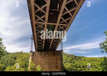 The steel lattice structure of the railway bridge viewed from below against the blue sky. Stock Photo