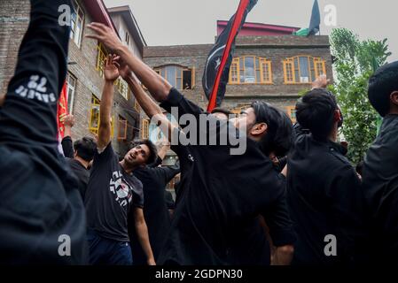 Srinagar, India. 14th Aug, 2021. Kashmiri Shia Muslims beat their chests as they mourn during a muharram procession in Srinagar. Muharram is the first month of Islam. It is one of the holiest months in the Islamic calendar. Shia Muslims commemorate Muharram as a month of mourning in remembrance of the Martyrdom Islamic Prophet Muhammad's grandson Imam Hussain, who was killed on Ashura (10th day of Muharram) in the battle of Karbala in 680 A.D. Credit: SOPA Images Limited/Alamy Live News Stock Photo