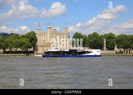 Tourist cruise boat passing the Tower of London, on the River Thames, in Lonodn, UK Stock Photo