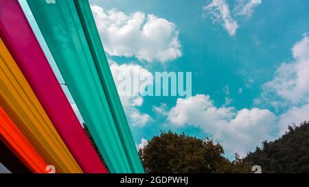 colorful strips in the wood and under the blue cloudy sky. blue, pink, orange, yellow strips on the sky Stock Photo