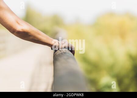 Arm of a woman with a bracelet leaning on a wooden railing Stock Photo
