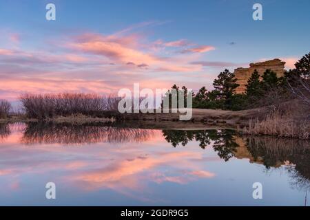 Glassy reflection of pink clouds and blue skies at sunset near Monument Rock in the Front Range of the Rocky Mountains in Colorado Stock Photo