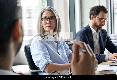 Smiling female ceo looking at male manager colleague at table meeting. Stock Photo