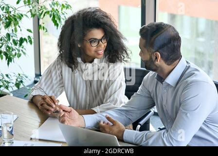 Female smiling trainee listening to indian ceo mentor leader at office meeting. Stock Photo