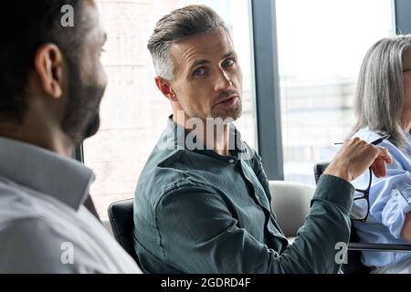 Serious mature ceo executive talking to African American manager in boardroom. Stock Photo