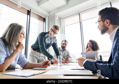 Mature businessmen leader talking with project team at meeting in board room. Stock Photo