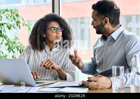 Indian ceo mentor leader talking to female trainee using laptop at meeting. Stock Photo