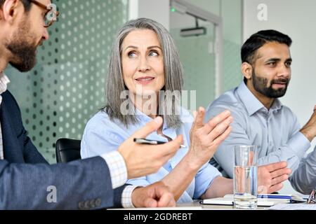 Smiling female ceo discussing project with managers colleague at table meeting. Stock Photo