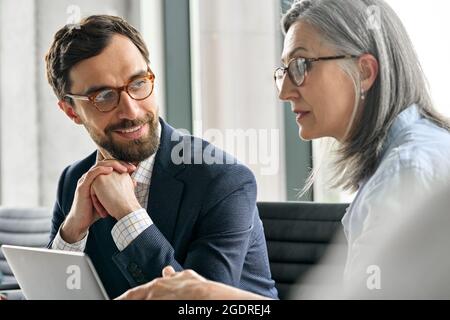 Male smiling executive manager listening to female ceo mentor leader at office. Stock Photo