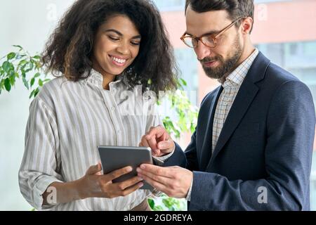Mentor ceo holding tablet device and female manager discuss project in office. Stock Photo