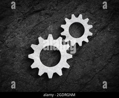 White stone gear symbol for repair maintenance or mechanism symbol on dark stone wall background Stock Photo