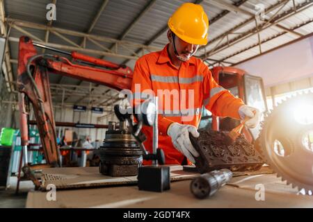 A mechanic man Small Excavator Repair and Maintenance. asian Heavy Equipment Mechanic Trying to Find an Issue. Industrial Theme. Stock Photo