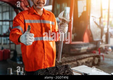 Thumbs up of excavator repair technician with large iron wrench in a hand, Powerful Professional Mechanic. Heavy Duty Equipment Maintenance. Industria Stock Photo